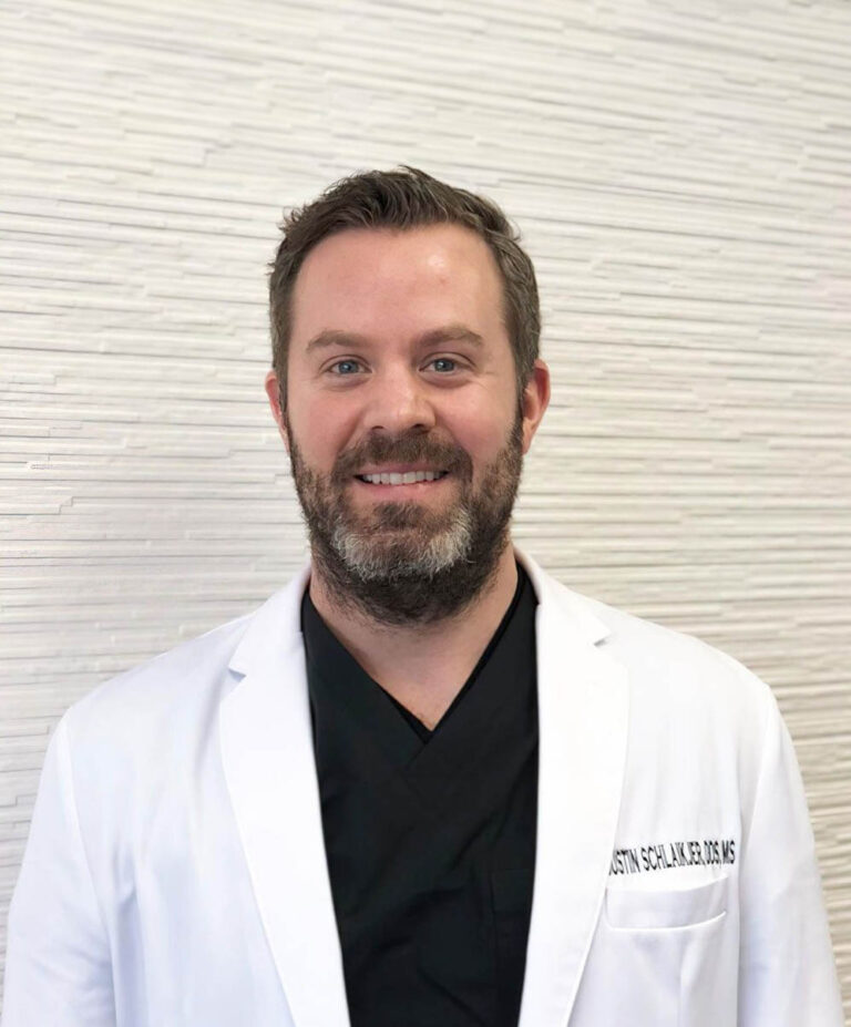 Portrait of Dr. Justin M. Schlaikjer, DDS, MS, St. Louis periodontist in white coat