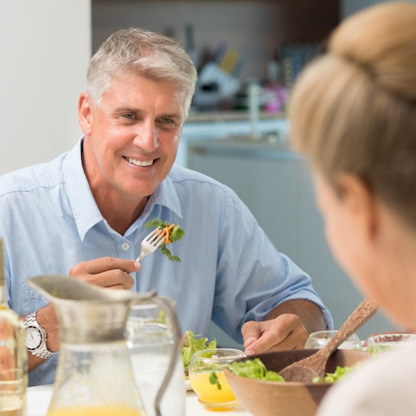 Older man confidently enjoying a salad after receiving dental implants at Dr. Schlaikjer’s Sunset Hills office.